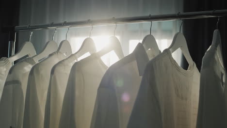 Rack-with-hangers-of-white-clothes-in-the-rays-of-the-sun-from-the-window