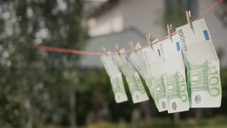 Several-banknotes-of-one-hundred-euros-are-drying-on-a-clothesline.-Money-laundering-concept.-Side-view