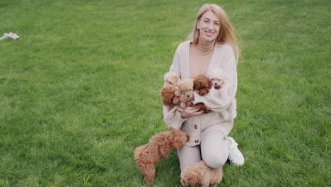 Attractive-pregnant-woman-playing-with-several-puppies-on-the-lawn
