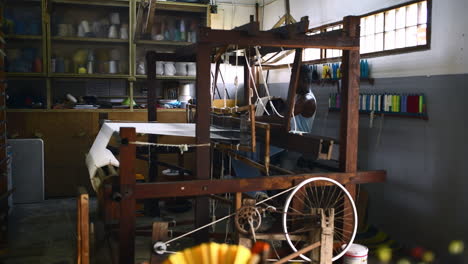 a-young-man-operating-a-floor-treadle-loom-inside