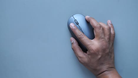 Hand-with-computer-mouse-on-gray--background-,