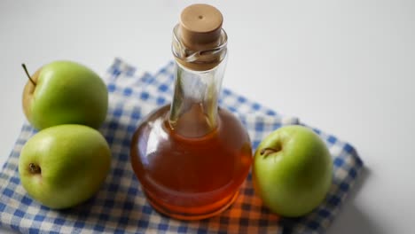 Apple-vinegar-in-glass-bottle-with-fresh-green-apple-on-table-,