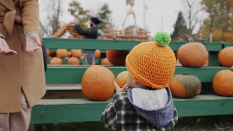 Kid-have-fun-at-the-fair-in-honor-of-Halloween,-carries-a-pumpkin
