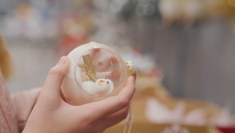 The-buyer-holds-a-toy-snowman-in-his-hands---chooses-decorations-for-the-Christmas-tree