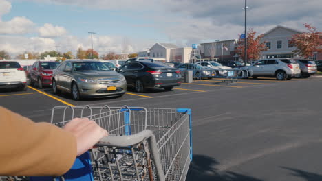 Lockport,-NY,-USA,-October-2021:-A-shopper-drives-a-shopping-cart-towards-Walmart-supermarket-in-the-USA
