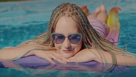 Happy-Girl-with-afro-pigtails,-swims-on-an-inflatable-mattress-in-the-pool,-resting-and-enjoying-the-rest