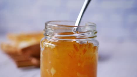 Spoon-pick-orange-fruit-jelly-from-a-container