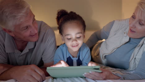 Grandparents,-kid-and-tablet-on-bed