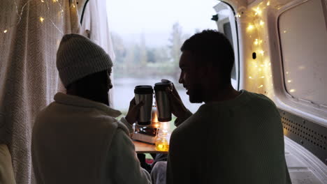 Couple,-cheers-and-coffee-while-camping-in-caravan