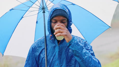 Rain,-umbrella-and-coffee-with-black-man-in-nature