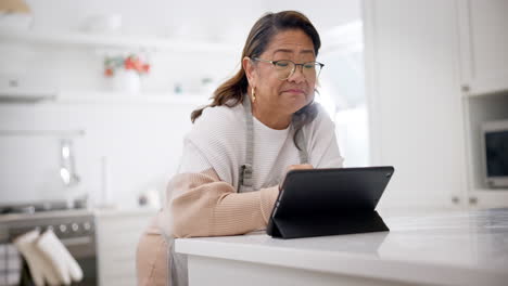 Kitchen,-smile-and-senior-woman-with-tablet