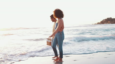 Couple,-beach-walk-and-picnic-basket-for-holiday