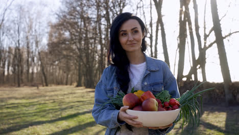 Caucasian-woman-holding-a-tray-with-fruits-and-vegetables-while-walking-through-the-countryside