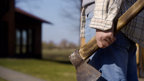Close-up-view-of-man-hand-holding-ax-in-the-countryside
