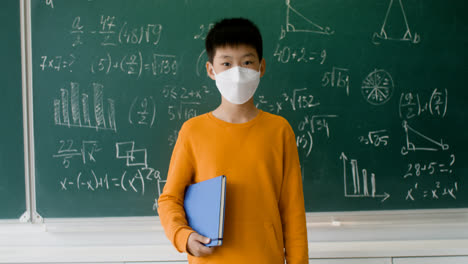 Asiatischer-Schüler-Mit-Gesichtsmaske,-Der-In-Die-Kamera-Schaut.