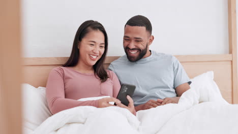 Home-bed,-phone-and-happy-couple-laughing-at-funny