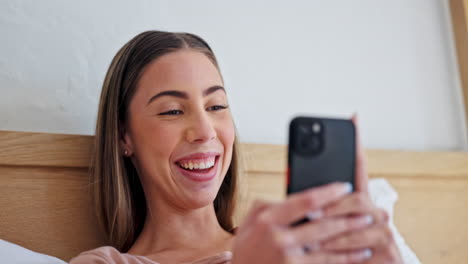 Woman,-phone-and-texting-with-laugh-in-bed