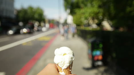 Man-holding-ice-cream-point-of-view-walking-through-city