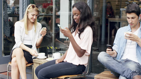 Jóvenes-Que-Utilizan-Teléfonos-Inteligentes-Móviles-Haciendo-Negocios-En-La-Cafetería