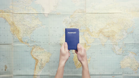 Top-view-hands-holding-american-passport-thumbs-up-gesture-vintage-world-map-from-above---Red-Epic-Dragon