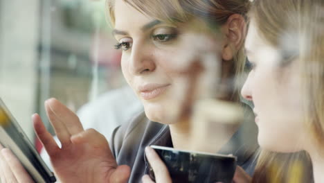 Zwei-Frauen-Nutzen-Ein-Digitales-Tablet-Und-Trinken-Kaffee-Im-Café
