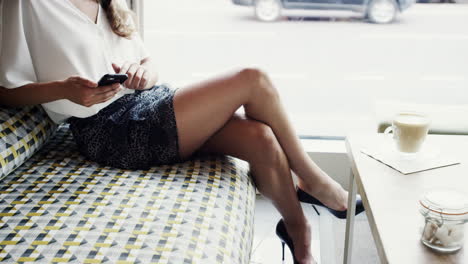 Attractive-business-woman-sexy-legs-using-mobile-smart-phone-cafe-city-commuters-in-background