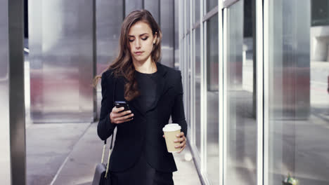 Attractive-business-woman-commuter-using-smartphone-walking-in-city-of-london