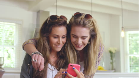 Two-beautiful-friends-planning-road-trip-using-smart-phone-at-home