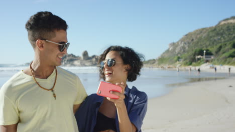 Schönes-Gemischtrassiges-Paar,-Das-Selfies-Am-Strand-Macht-Und-Lustige-Gesichter-Zieht
