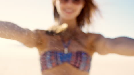 Close-up-of-pretty-girl--pouring-sand-running-through-fingers-slow-motion-at-the-beach-with-sun-flare-and-blue-skye