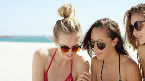 Three-teenage-girl-friends-taking-selfie-on-beach-wearing-colorful-bikini-sharing-vacation-photo