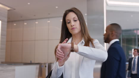 Attractive-successful-businesswoman-leaving-corporate-office-lobby-checking-smartwatch