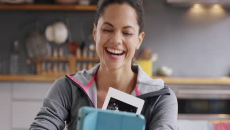 Excited-mixed-race-woman-sharing-she-is-pregnant-with-ultrasound-over-video-chat-using-digital-tablet-at-home
