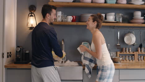 Newly-wed-in-love-couple-dancing-at-home-washing-dishes-wearing-pajamas-having-fun