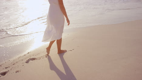 Schöne-Frau-In-Weißem-Kleid,-Die-Bei-Sonnenuntergang-Am-Strand-Spaziert,-In-Zeitlupe,-Roter-Drache