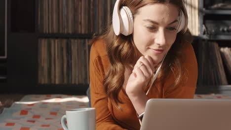 Hermosa-Mujer-Escuchando-Música-En-Una-Computadora-Portátil-En-Casa-Con-Auriculares-Tomando-Café