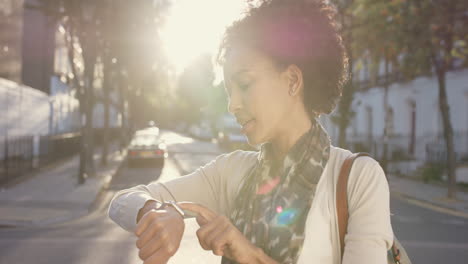 Beautiful-Mixed-race-woman-using-smart-watch-technology-walking-through-city