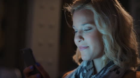 Schöne-Blonde-Frau,-Die-Nachts-Zu-Hause-Smartphone-Technologie-Nutzt