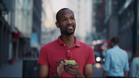 Zeitlupenporträt-Eines-Glücklichen-Afroamerikanischen-Mannes,-Der-Sein-Smartphone-Benutzt