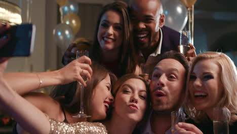 Smiling-group-of-friends-celebrate-evening-event-with-selfie-at-party