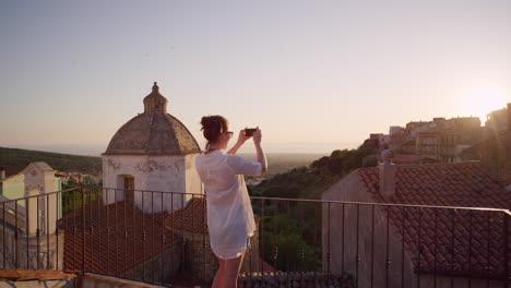 happy-woman-using-smartphone-taking-photo-of-beautiful-sunset-enjoying-sharing-summer-vacation-travel-experience-on-balcony