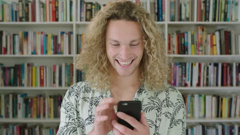 close-up-portrait-of-attractive-young-caucasian-man-student-smiling-happy-using-smart-phone-mobile-technology-enjoying-internet-research-online-in-college-library