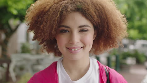 Nahaufnahme-Porträt-Einer-Lebhaften-Jungen-Teenager-Studentin,-Die-Lächelt-Und-In-Die-Kamera-Schaut,-Während-Sie-Mit-Der-Hand-Durchs-Haar-Läuft.-Süße-Frau-Mit-Trendiger-Afro-Frisur