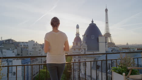 Mujer-Joven-Usando-Un-Teléfono-Inteligente-Tomando-Fotos-Disfrutando-Compartiendo-Experiencias-De-Vacaciones-De-Verano-En-París-Fotografiando-La-Hermosa-Vista-Del-Atardecer-De-La-Torre-Eiffel-En-El-Balcón