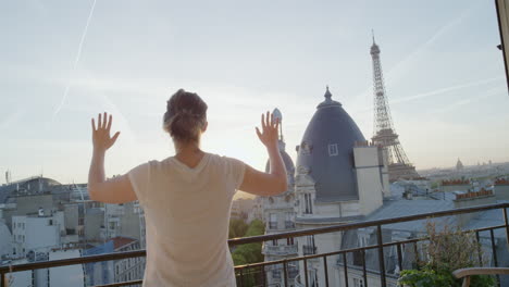 Mujer-Que-Usa-Auriculares-De-Realidad-Virtual-Y-Disfruta-Explorando-La-Experiencia-Del-Ciberespacio-En-Línea-En-El-Balcón-De-La-Hermosa-Torre-Eiffel-Al-Atardecer-De-París