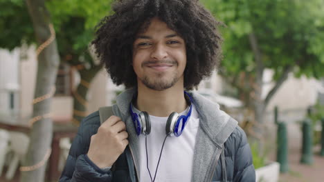 portrait-of-young-confident-mixed-race-student-man-smiling-happy-looking-at-camera-commuting-in-city-enjoying-urban-lifestyle-cool-afro-hairstyle