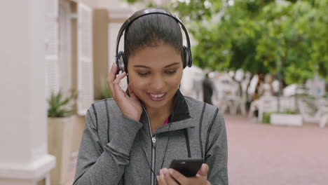 portrait-of-beautiful-mixed-race-woman-enjoying-listening-to-music-wearing-headphones-texting-browsing-using-smartphone-mobile-technology-in-city