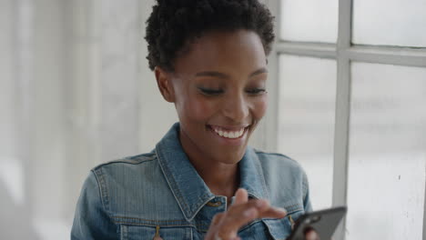 Porträt-Einer-Jungen-Afroamerikanischen-Frau,-Die-SMS-Schreibt-Und-Mit-Dem-Smartphone-In-Den-Sozialen-Medien-Surft-Und-Mobile-Kommunikation-Genießt,-Die-Am-Fenster-Steht