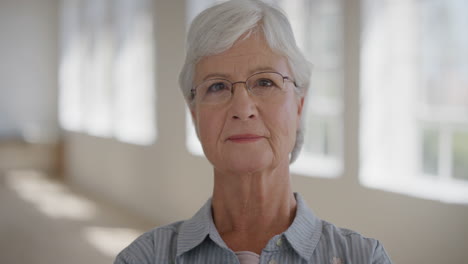 portrait-of-beautiful-elderly-retired-woman-looking-pensive-at-camera-wearing-glasses-in-apartment-background