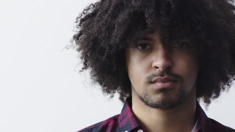 close-up-portrait-of-young-mixed-race-man-looking-serious-at-camera-with-trendy-afro-hairstyle-on-white-background-copy-space